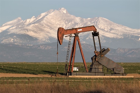 Oil rig pump with Rocky Mountains in the background